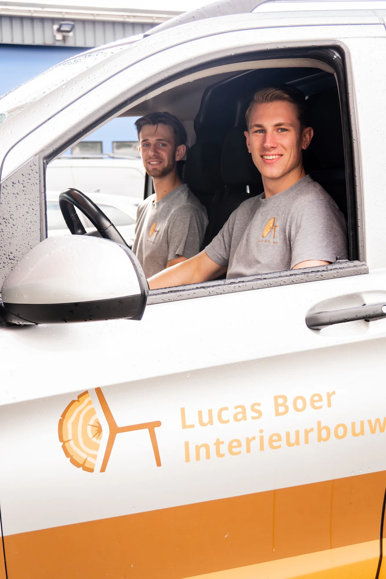 Twee van het team in de bus met het logo van Lucas Boer Interieurbouw op de deur