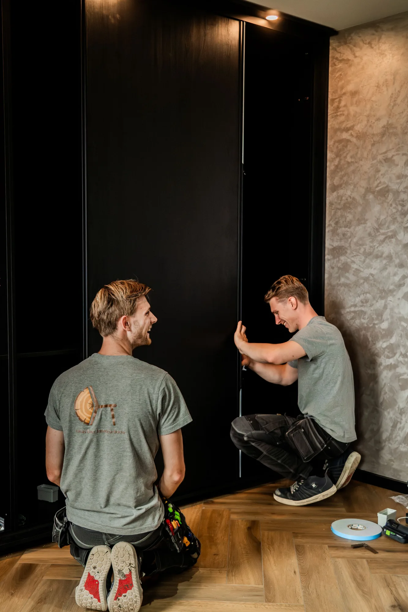 Twee van het team stellen samen de schuifdeuren van een zwarte kastenwand af