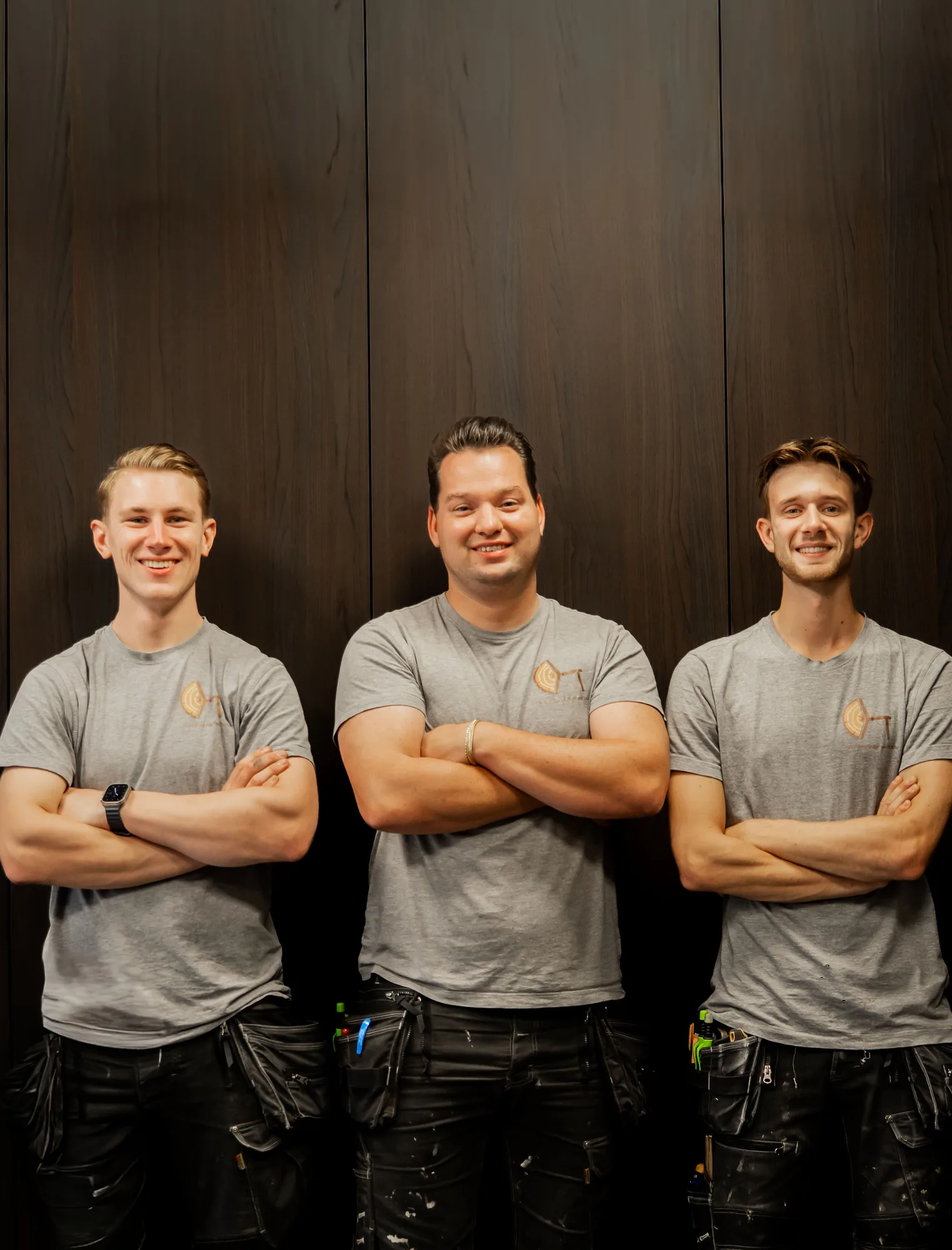 Het team van Lucas Boer Interieurbouw, drie man in grijze bedrijfsshirts voor een kastenwand in noten
