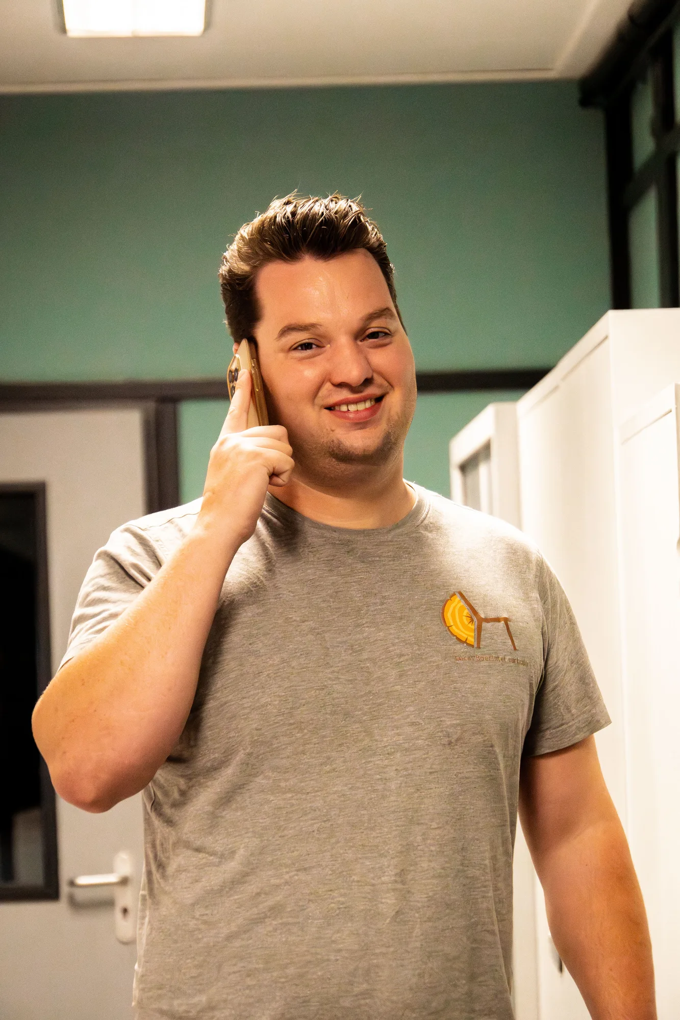 Lucas aan de telefoon, in het grijze bedrijfsshirt