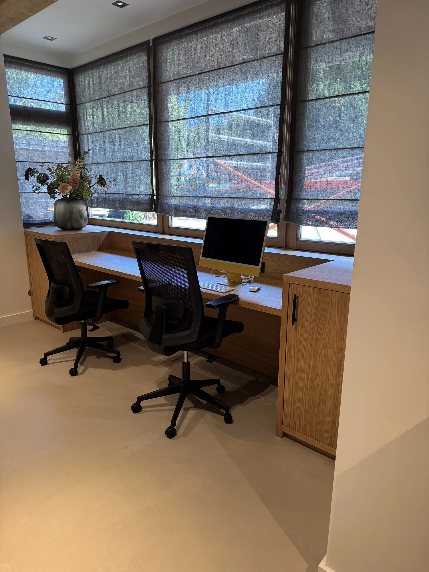 Bureau in eiken over de volle breedte van de raampartij, met twee werkplekken en een kast aan het eind