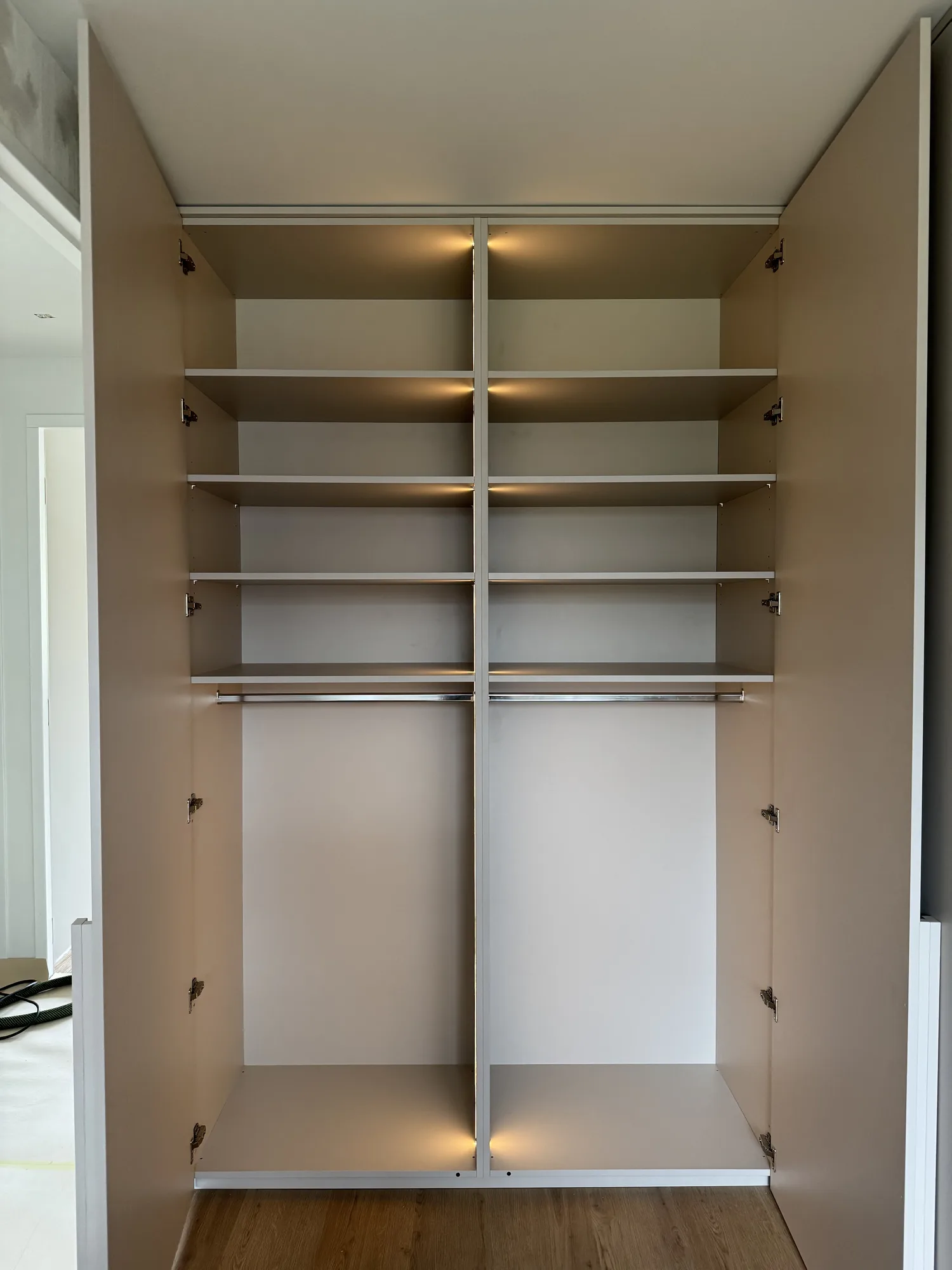 De kastenwand met de deuren open: schappen boven, roedes onder