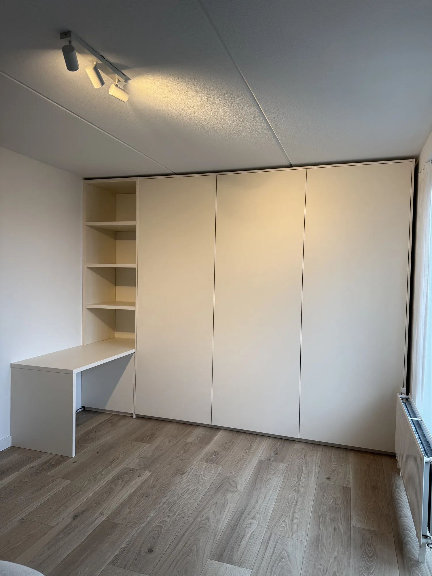 Kastenwand in creme met een bureaublad en open schappen aan de zijkant