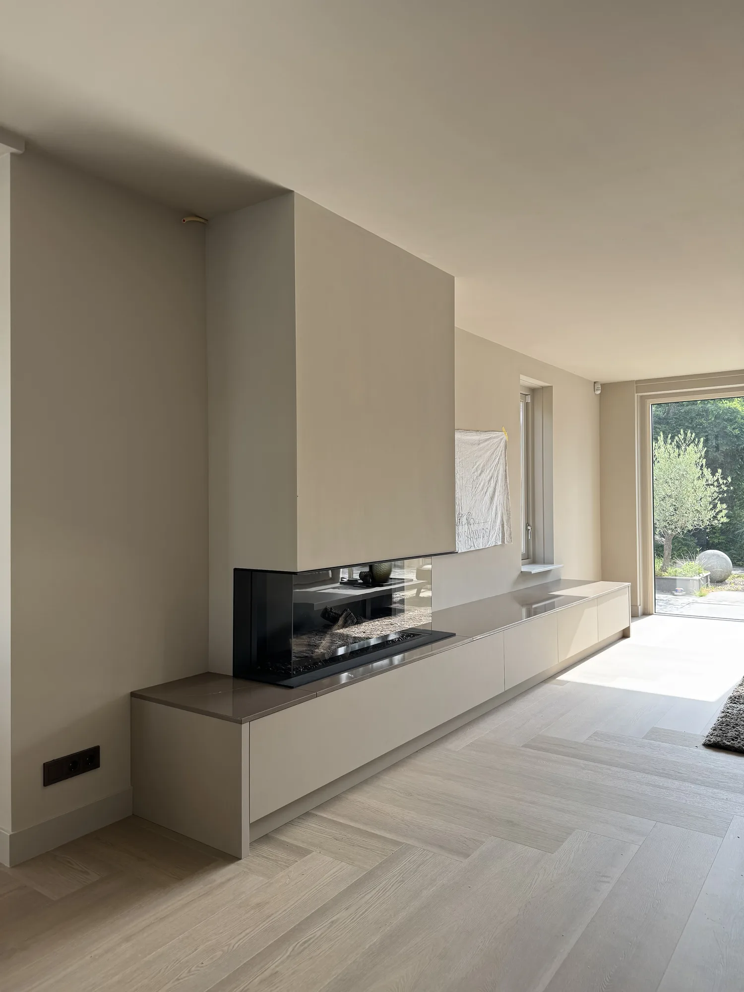 Tv-wand in taupe met een haard en een laag meubel over de volle breedte