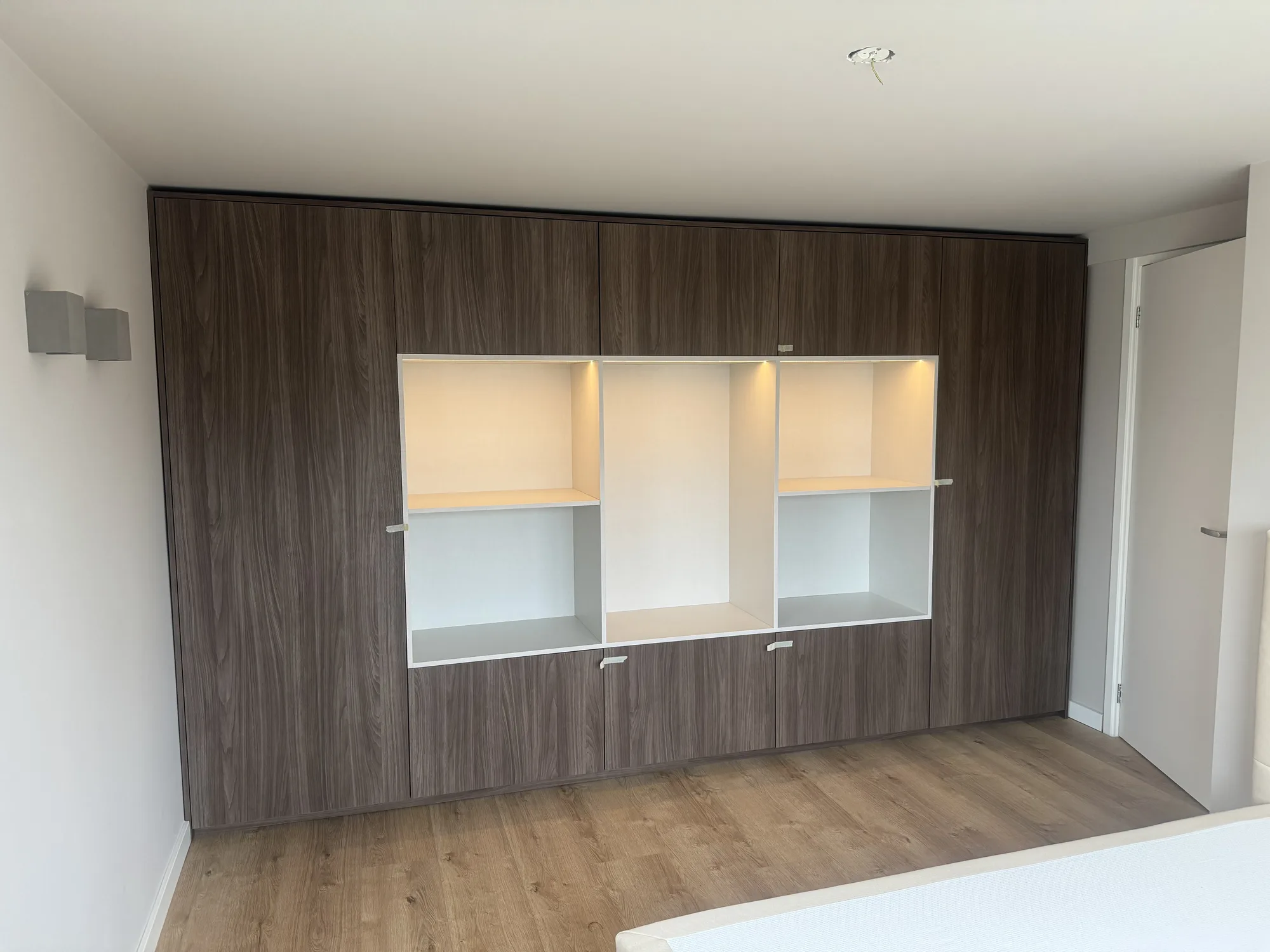 Wandkast in donker eiken met drie verlichte open vakken in het midden