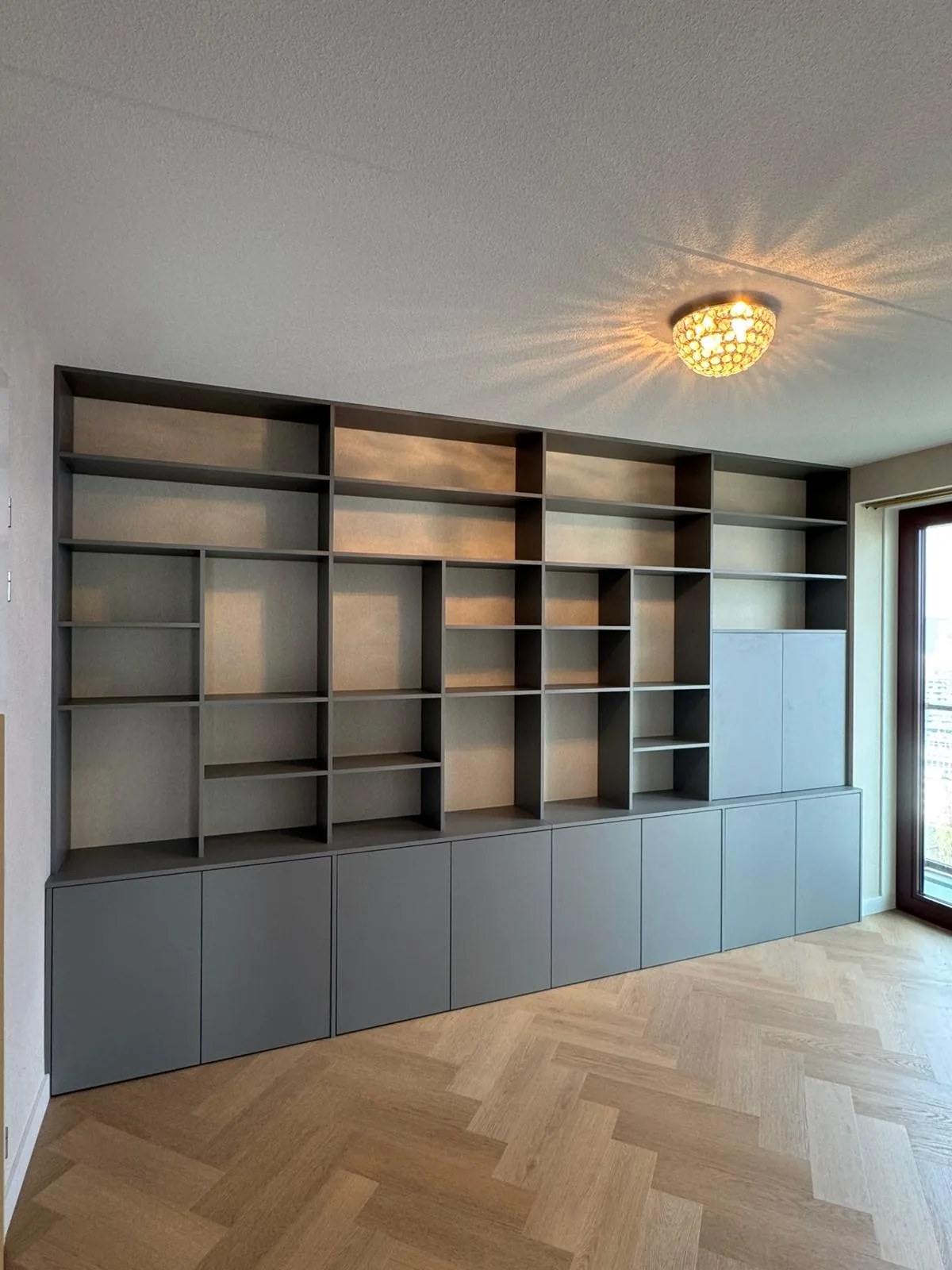 De grijze kastenwand van dichterbij, op een visgraatvloer