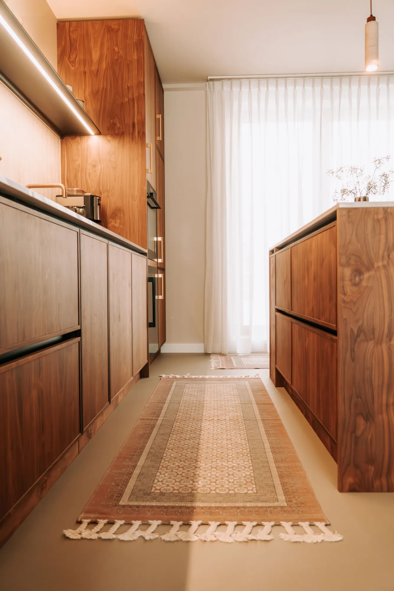 Zicht door de keuken met links de kastenwand en rechts het eiland