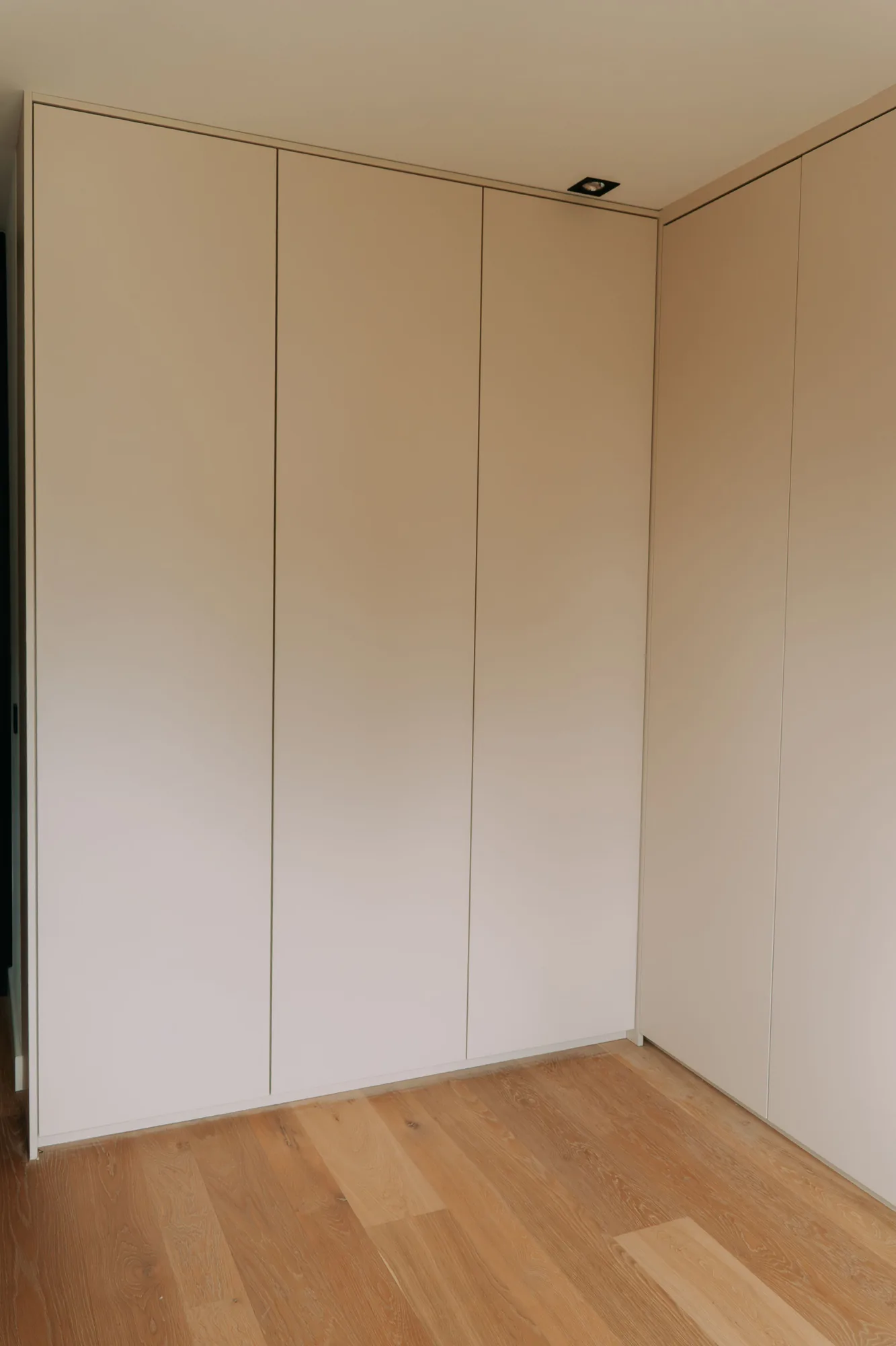 Greeploze kastenwand in creme die doorloopt tot tegen het plafond