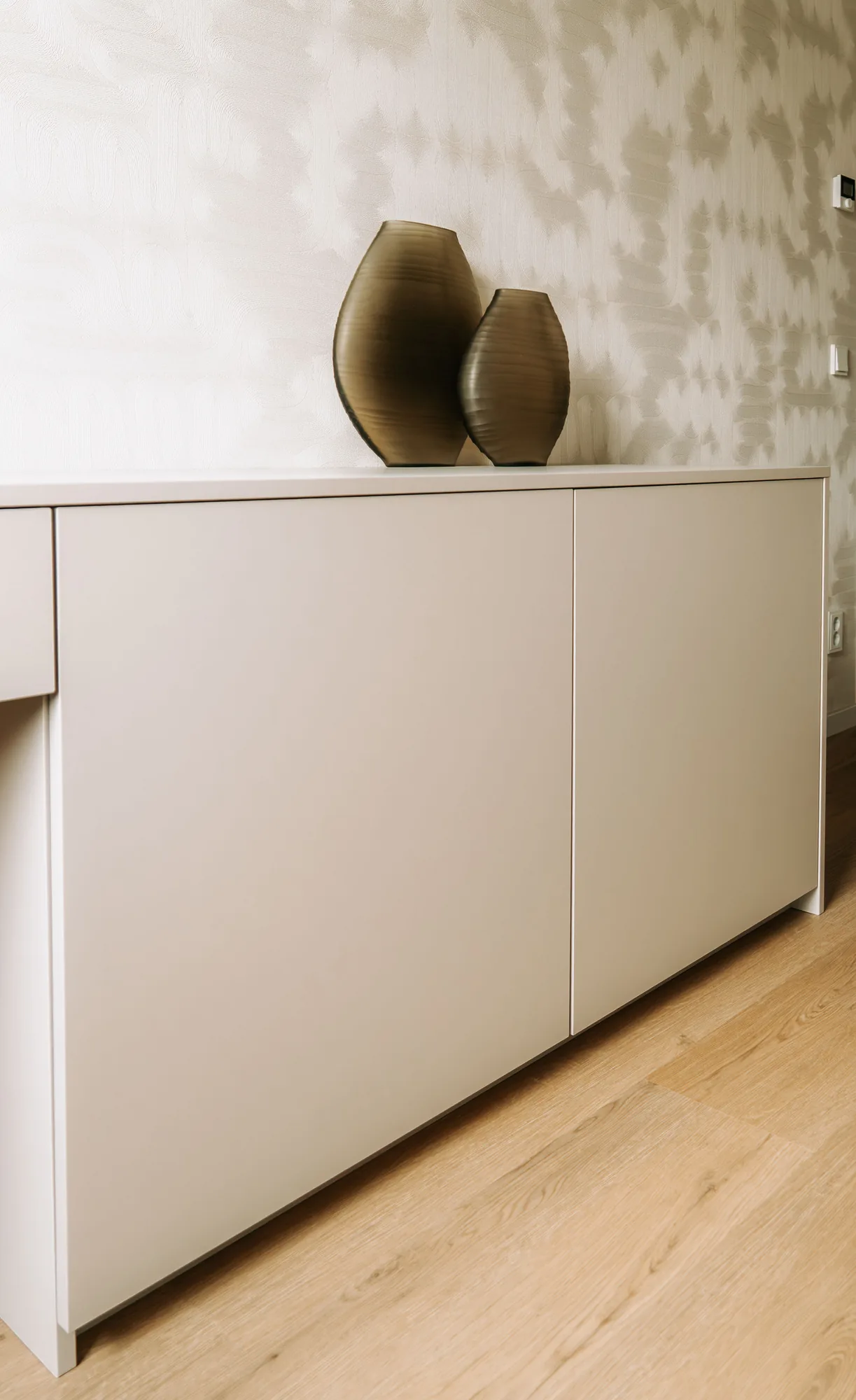 Dressoir in taupe met twee vazen erop, in de gang