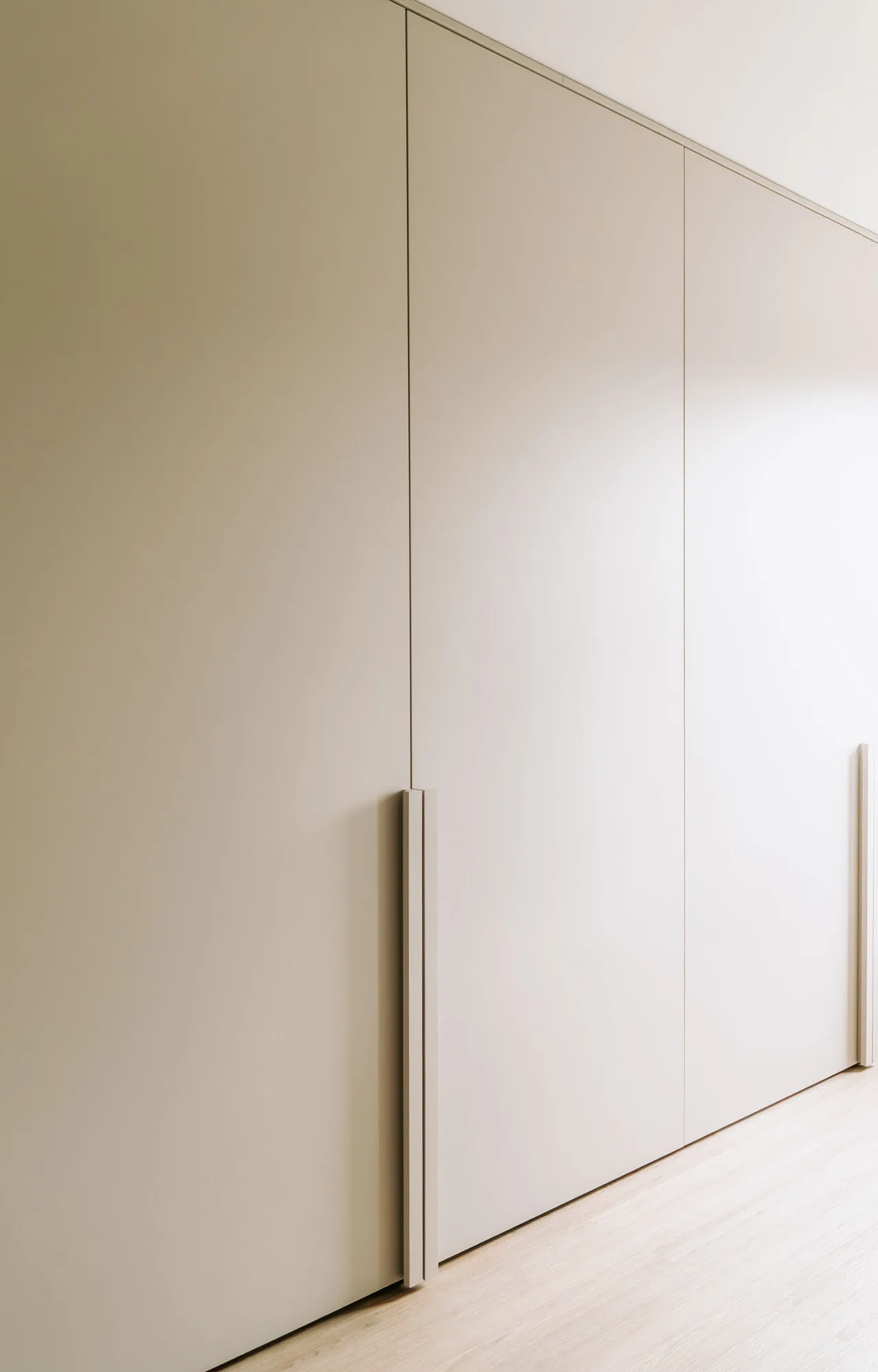 Detail van de lange grepen op de taupe kastdeuren