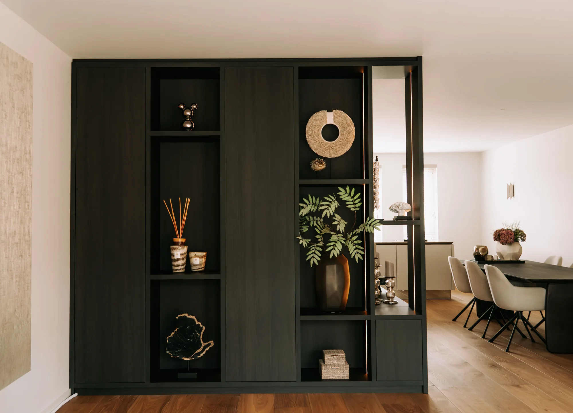 Zwarte roomdivider met open vakken tussen de zithoek en de eettafel