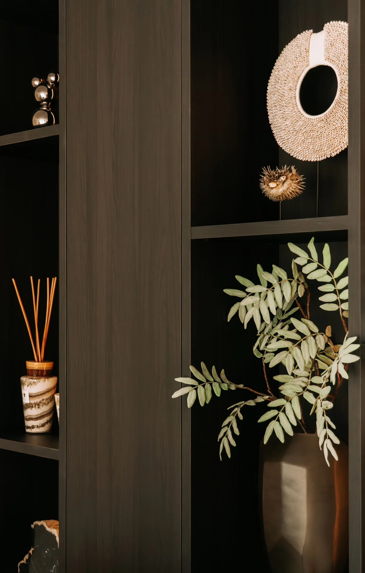 Detail van de open vakken met een plant en geurstokjes