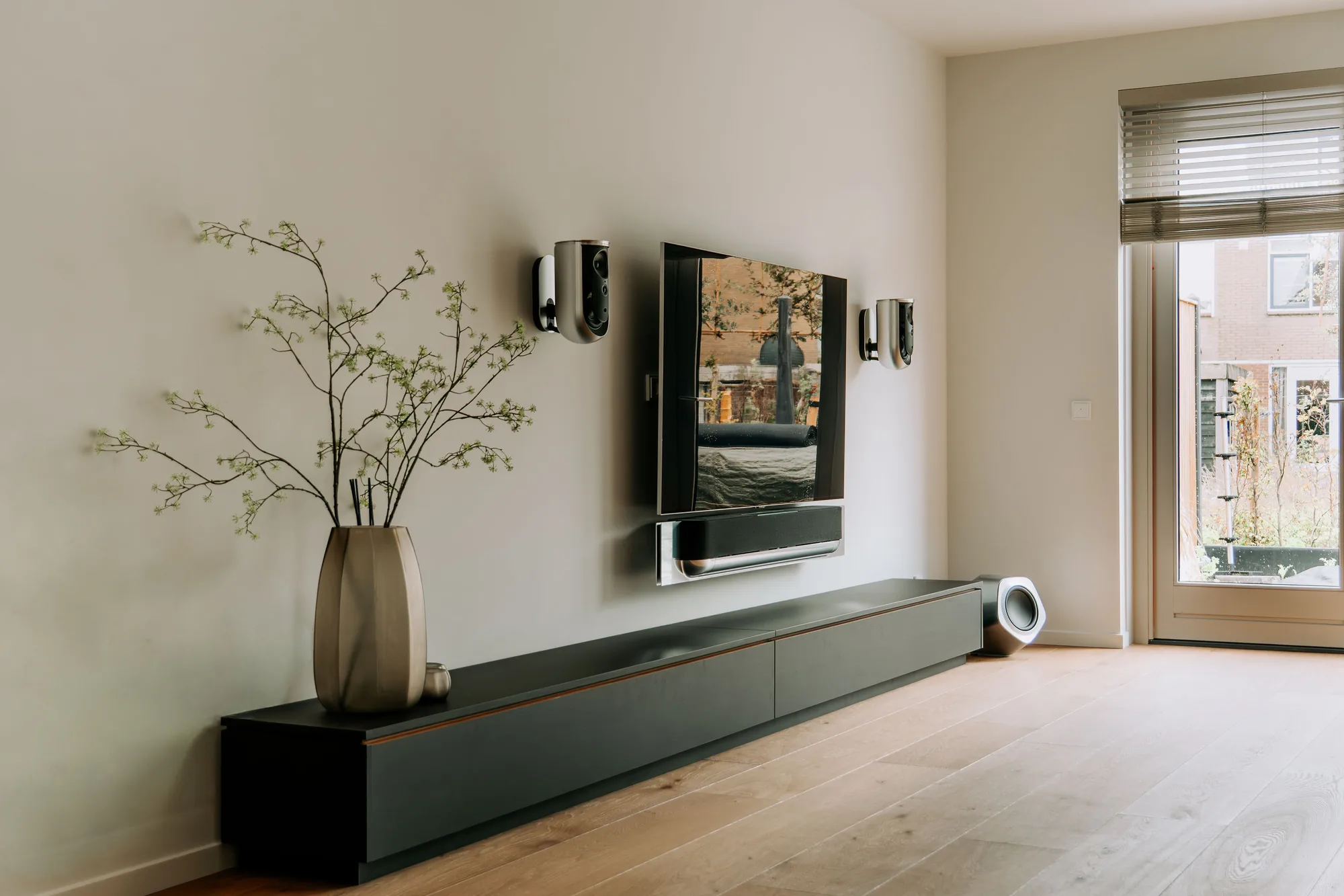 Zwart tv-meubel over de volle breedte van de wand, met de televisie erboven